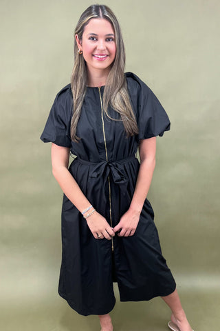 Woman wearing a black dress against a green background