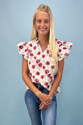 Woman wearing a floral blouse and jeans against a blue background