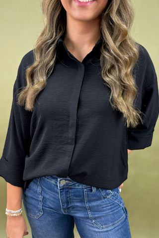 Person wearing a black shirt and blue jeans against a green background