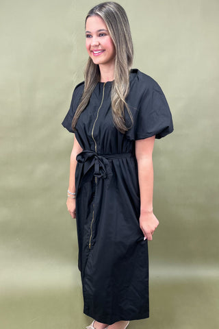Woman wearing a black dress against a beige background