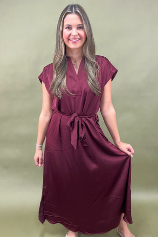 Woman wearing a burgundy dress against a green background