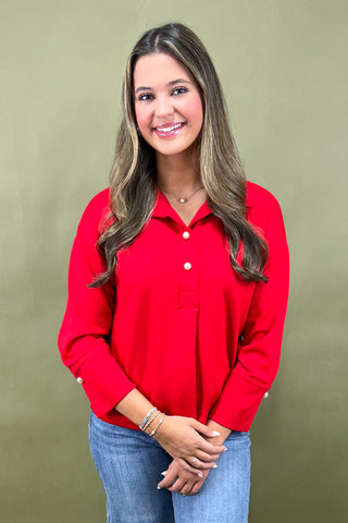 Woman wearing a red shirt and blue jeans against a green background