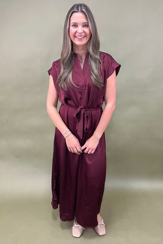 Woman wearing a burgundy dress against a plain background