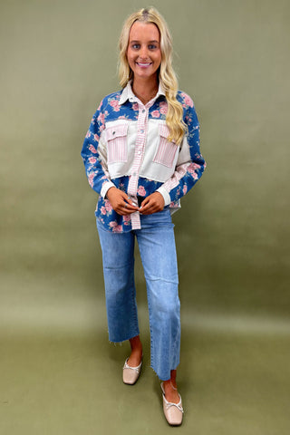 Woman wearing a floral shirt and jeans against a green background