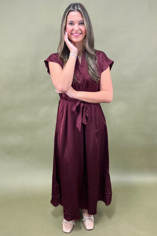 Woman wearing a burgundy dress against a green background