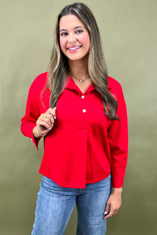 Woman wearing a red blouse and blue jeans against a green background