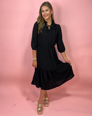 Woman wearing a black dress against a pink background