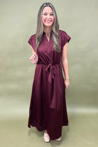 Woman wearing a burgundy dress against a green background