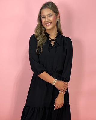 Woman wearing a black dress against a pink background