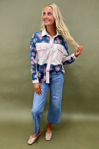 Woman wearing a floral shirt and jeans against a green background