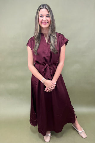 Woman wearing a burgundy dress against a green background