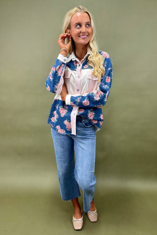 Woman wearing a floral blouse and jeans against a green background