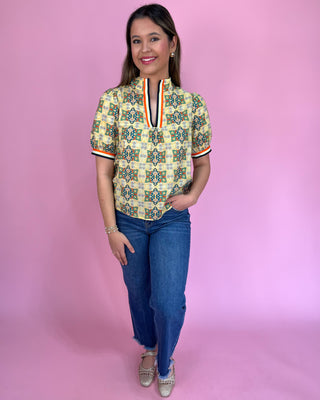 Woman wearing a patterned shirt and jeans on a pink background