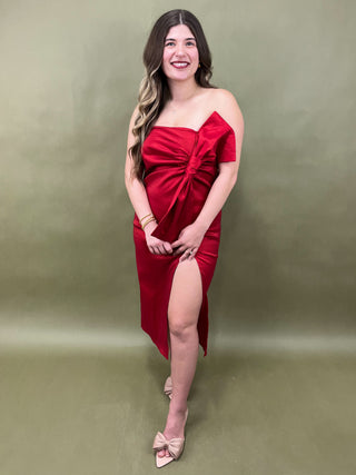 Woman in a red strapless dress posing against a green background