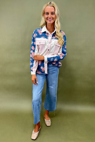 Woman wearing a floral shirt and jeans against a green background
