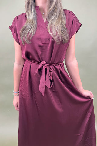 Woman wearing a burgundy dress with a plain background