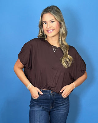 Chocolate brown dolman sleeve top with a relaxed fit, crew neckline, and gathered hem.