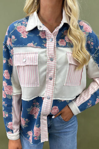 Person wearing a floral and striped denim jacket with a neutral background