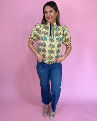 Woman wearing a patterned shirt and jeans on a pink background
