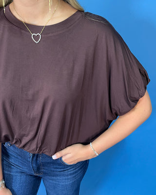 Chocolate brown dolman sleeve top with a relaxed fit, crew neckline, and gathered hem.