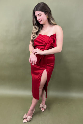 Woman wearing a red strapless dress with a slit on a green background