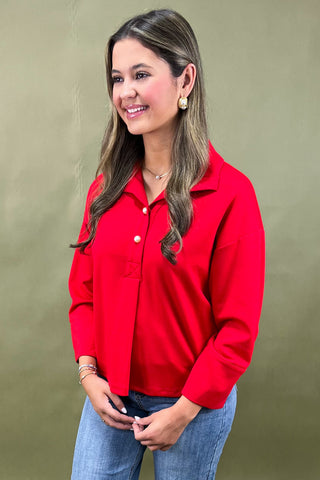 Woman wearing a red shirt and blue jeans against a green background