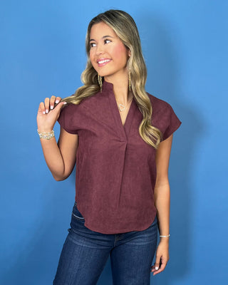 Burgundy cap sleeve blouse with a split V-neckline, subtle textured finish, and relaxed fit.