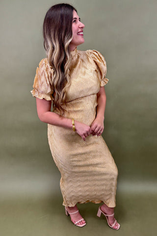 Woman wearing a gold dress against a green background
