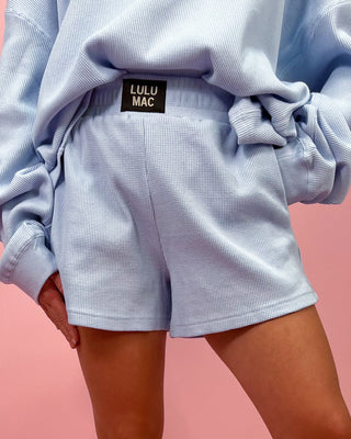 Light blue textured outfit with 'LULU MAC' label on a pink background
