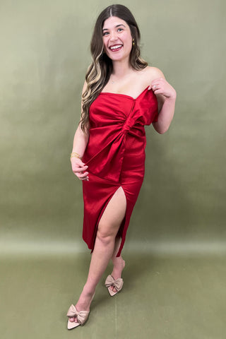 Woman in a red strapless dress with a green background
