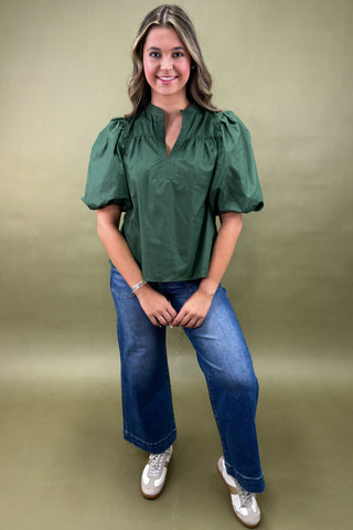 Woman wearing a green blouse and blue jeans against a green background