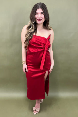 Woman wearing a red strapless dress with a bow detail on a green background