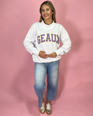 Woman wearing a white sweatshirt with 'GEAUX' text on a pink background