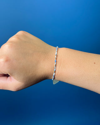 Enewton Hope Unwritten Bloopers Blue White and Gold Bracelet displayed on a solid blue background. 