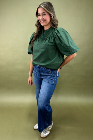 Woman wearing a green blouse and blue jeans on a green background