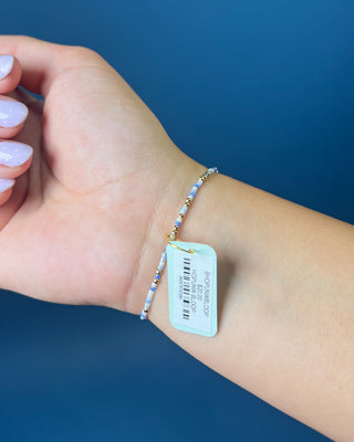 Enewton Hope Unwritten Bloopers Blue White and Gold Bracelet displayed on a solid blue background. 