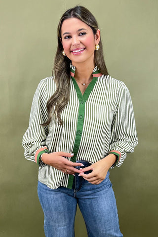 Woman wearing a striped shirt and jeans against a green background