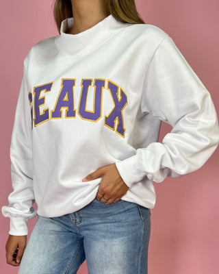 White sweatshirt with 'DEAUX' in purple and yellow on a pink background