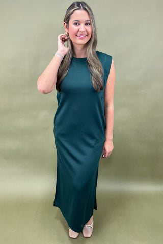 Woman wearing a teal sleeveless dress against a green background
