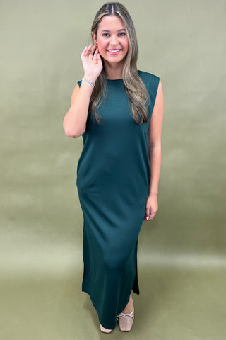 Woman wearing a teal sleeveless dress against a green background