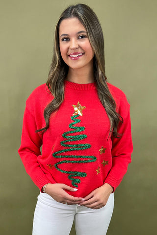 Woman wearing a red sweater with a Christmas tree design against a green background