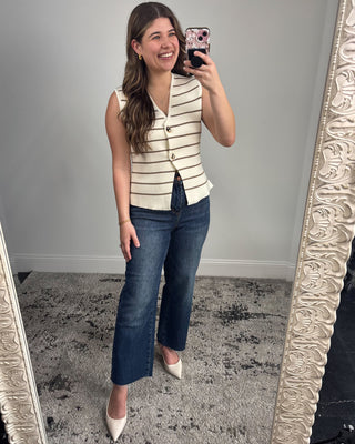 Woman taking a mirror selfie wearing a striped top and jeans.
