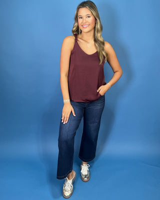 Burgundy sleeveless blouse with a V-neckline, braided shoulder straps, and a relaxed flowy fit.