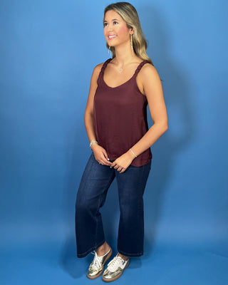 Burgundy sleeveless blouse with a V-neckline, braided shoulder straps, and a relaxed flowy fit.