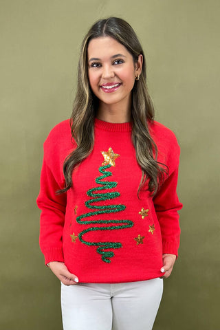 Woman wearing a red Christmas sweater with a tree design on a green background