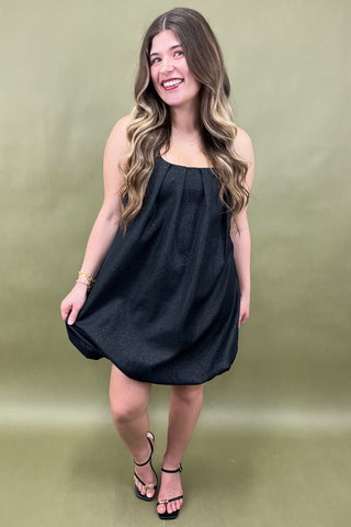 Woman wearing a black dress against a green background