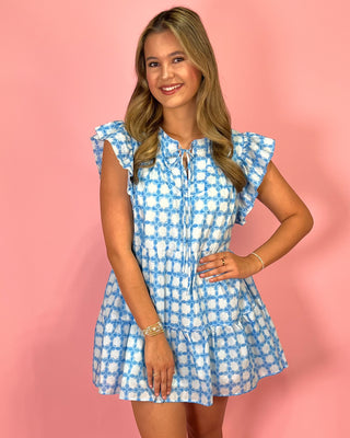 Woman wearing a blue and white checkered dress against a pink background