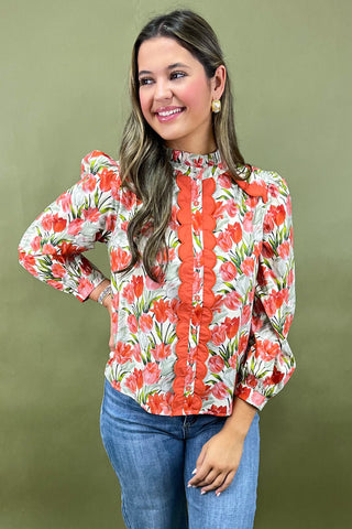 Woman wearing a floral blouse with long sleeves against a green background