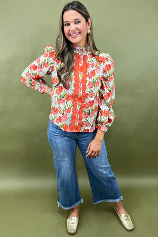 Woman wearing a floral blouse and blue jeans against a green background