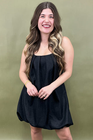 Woman wearing a black dress against a green background